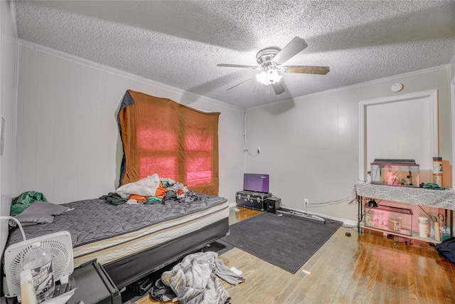 bedroom with a textured ceiling, hardwood / wood-style flooring, ceiling fan, and ornamental molding