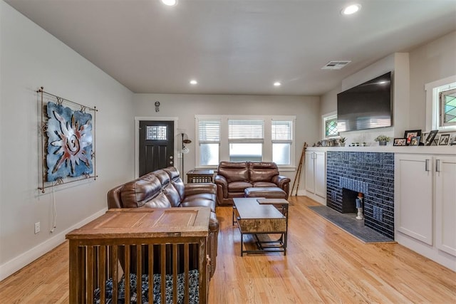 living room featuring light hardwood / wood-style flooring and a brick fireplace