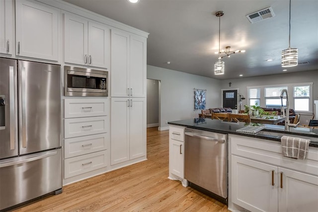 kitchen featuring stainless steel appliances, a chandelier, pendant lighting, light hardwood / wood-style floors, and white cabinets