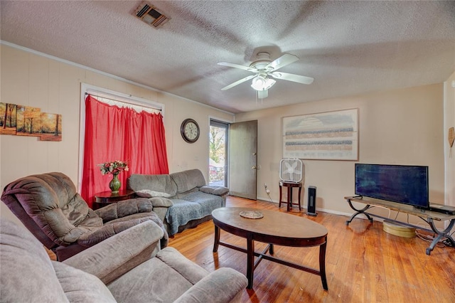 living room featuring ceiling fan, hardwood / wood-style floors, and a textured ceiling