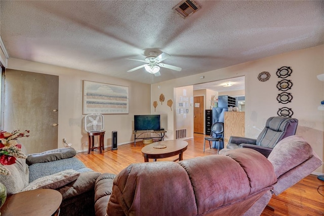 living room with a textured ceiling, light hardwood / wood-style flooring, and ceiling fan