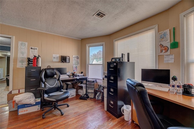 home office with light hardwood / wood-style floors and a textured ceiling