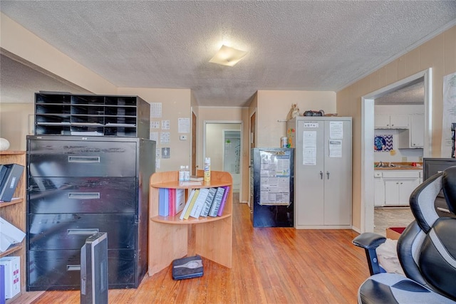 kitchen featuring sink, white cabinets, a textured ceiling, and light wood-type flooring