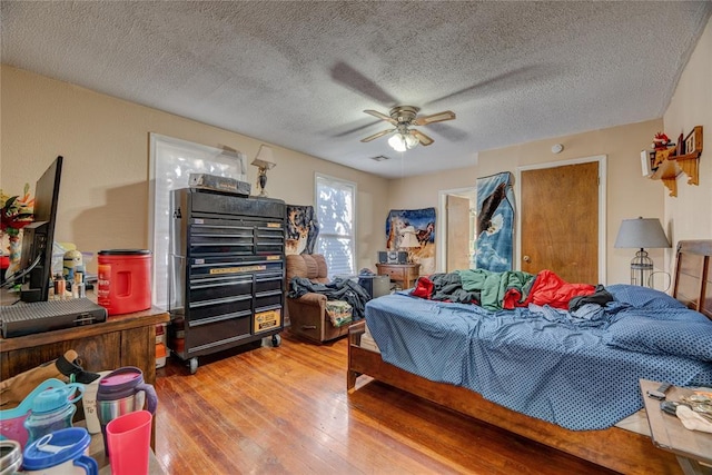 bedroom featuring ceiling fan, wood-type flooring, and a textured ceiling