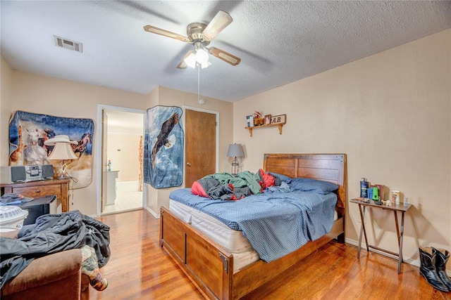 bedroom with ceiling fan, light hardwood / wood-style floors, and a textured ceiling