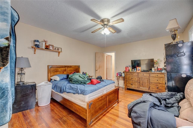 bedroom with a textured ceiling, light hardwood / wood-style flooring, and ceiling fan