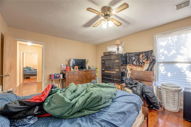 bedroom featuring hardwood / wood-style floors, a textured ceiling, and ceiling fan