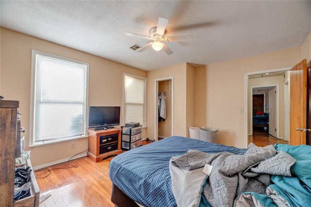 bedroom featuring ceiling fan, a closet, a spacious closet, and light wood-type flooring