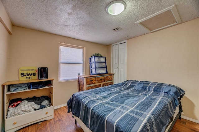 bedroom featuring a closet, wood-type flooring, and a textured ceiling