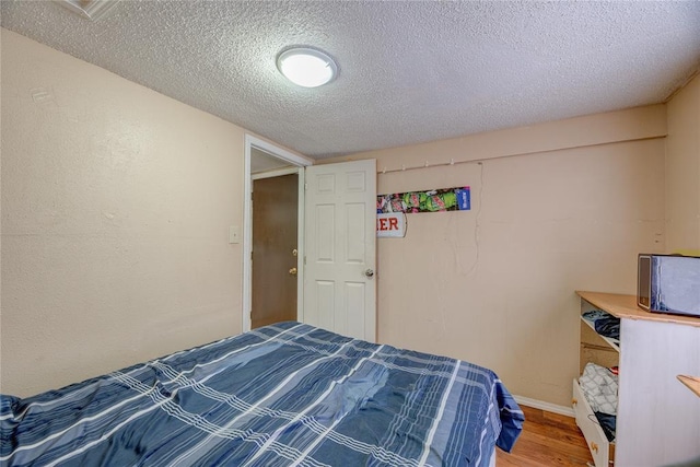 bedroom featuring hardwood / wood-style floors and a textured ceiling