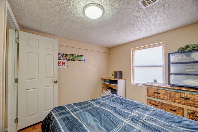 bedroom featuring hardwood / wood-style flooring and a textured ceiling