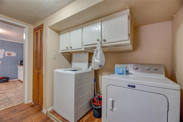 clothes washing area with cabinets, a textured ceiling, light hardwood / wood-style floors, and separate washer and dryer