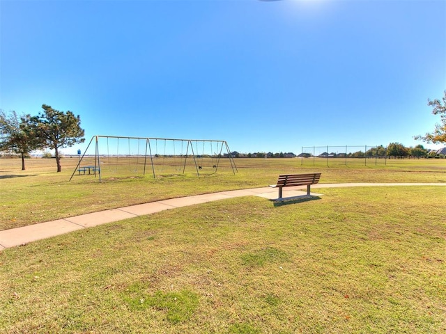 view of community with a playground, a lawn, and a rural view