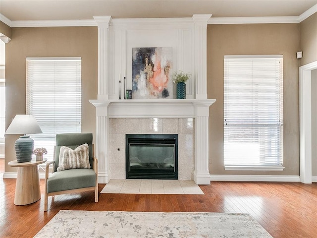 living room featuring a tiled fireplace, crown molding, and light hardwood / wood-style floors