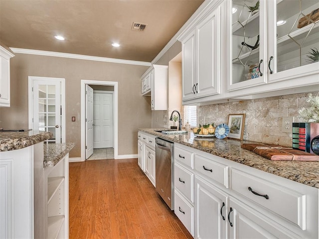 kitchen with dark stone counters, white cabinets, sink, stainless steel dishwasher, and light wood-type flooring