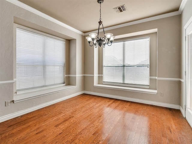 unfurnished dining area featuring a chandelier, crown molding, and wood-type flooring