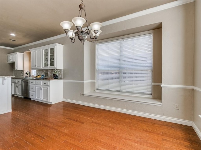 kitchen featuring white cabinets, an inviting chandelier, hardwood / wood-style flooring, and stainless steel dishwasher