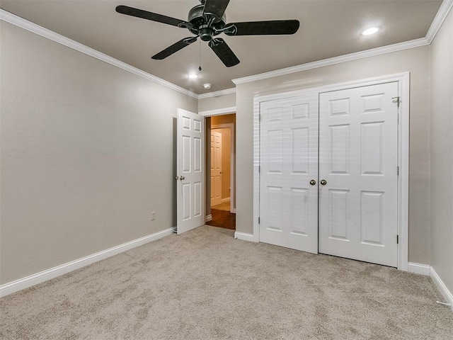 unfurnished bedroom with crown molding, ceiling fan, a closet, and light colored carpet