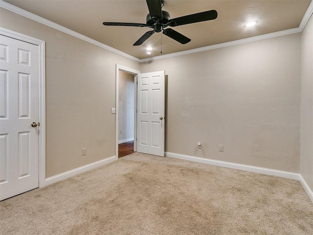 unfurnished bedroom featuring ceiling fan, light colored carpet, and ornamental molding