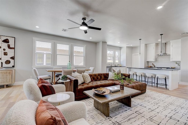 living room featuring ceiling fan, sink, and light hardwood / wood-style flooring