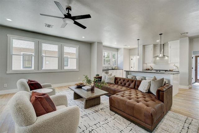 living room with ceiling fan, sink, and light hardwood / wood-style floors