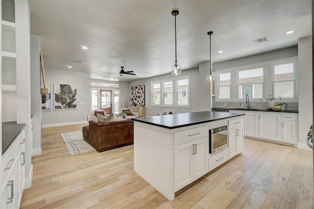 kitchen featuring a center island, pendant lighting, white cabinets, and light hardwood / wood-style floors