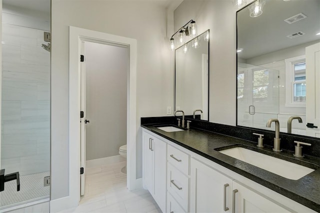 bathroom with a shower with door, vanity, and toilet