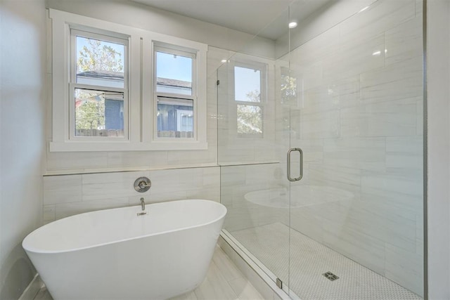 bathroom with shower with separate bathtub and tile walls