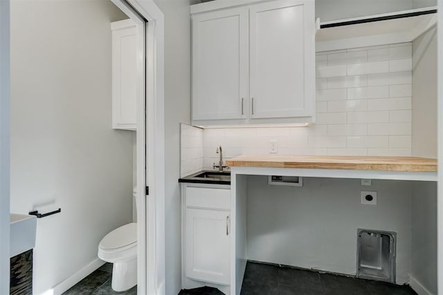 interior space featuring sink, cabinets, hookup for a washing machine, dark tile patterned floors, and hookup for an electric dryer