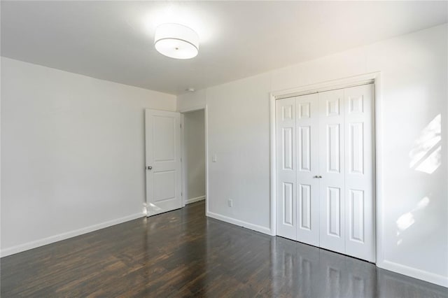 unfurnished bedroom with dark hardwood / wood-style flooring and a closet