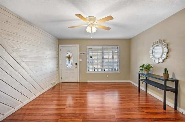 foyer entrance featuring ceiling fan, wood-type flooring, and a textured ceiling