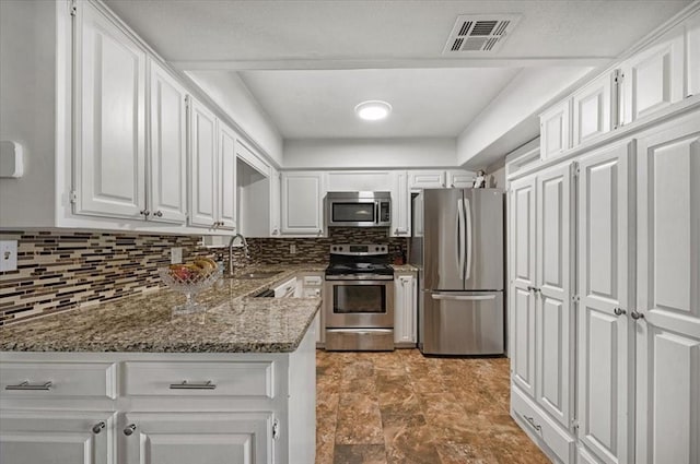 kitchen featuring backsplash, dark stone counters, white cabinets, sink, and stainless steel appliances