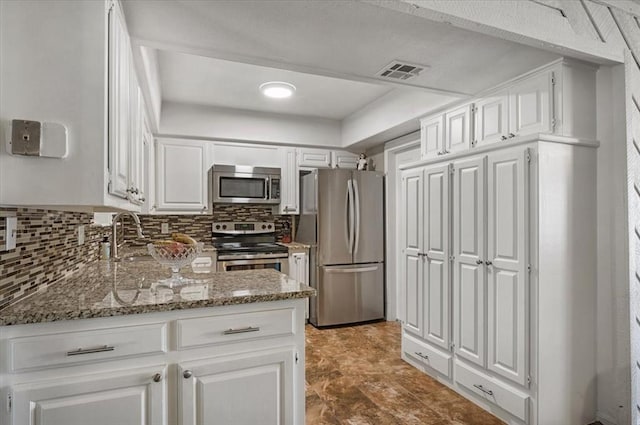 kitchen featuring light stone countertops, white cabinetry, sink, stainless steel appliances, and tasteful backsplash