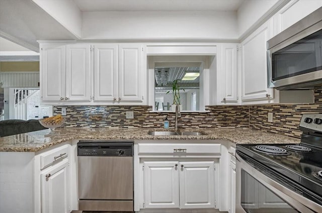 kitchen featuring tasteful backsplash, sink, white cabinets, and appliances with stainless steel finishes