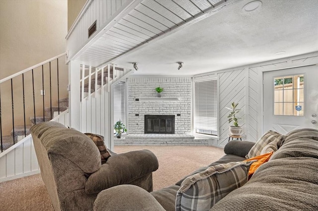 living room with carpet, a textured ceiling, and a brick fireplace