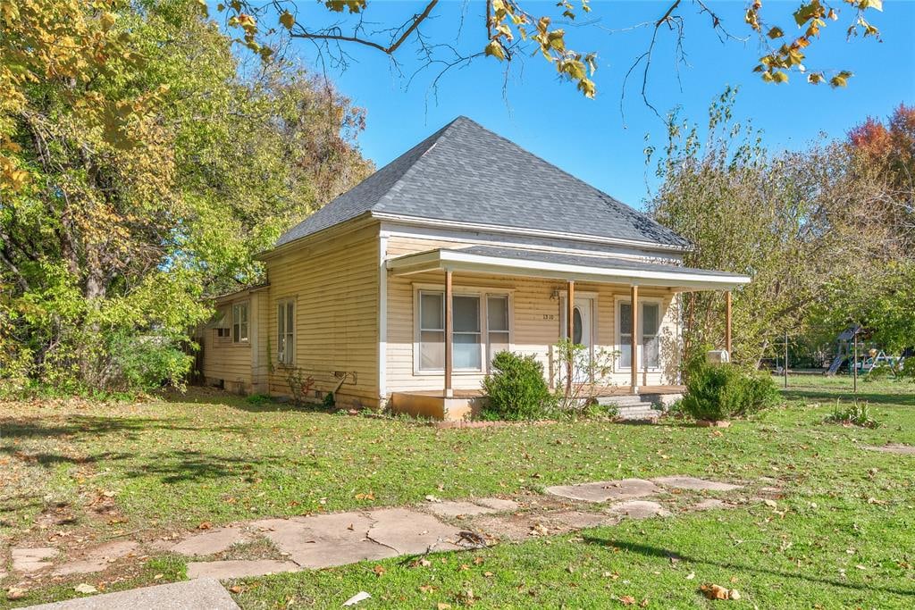 farmhouse inspired home with covered porch and a front lawn