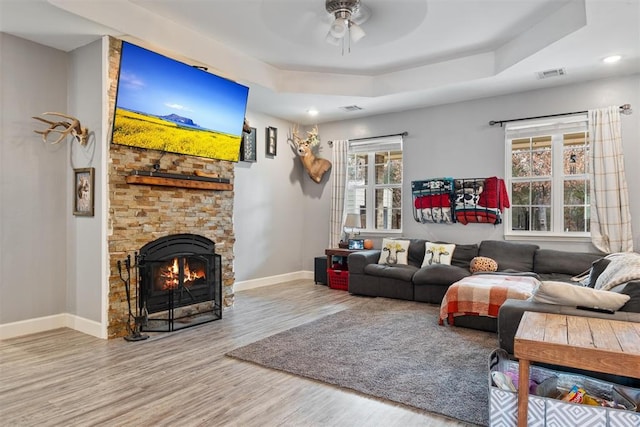 living room with wood-type flooring, a tray ceiling, and ceiling fan