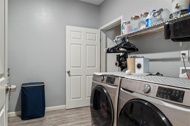 laundry room featuring baseboards, separate washer and dryer, wood finished floors, and laundry area