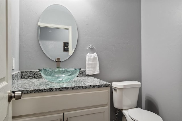 bathroom featuring vanity, toilet, and a textured wall