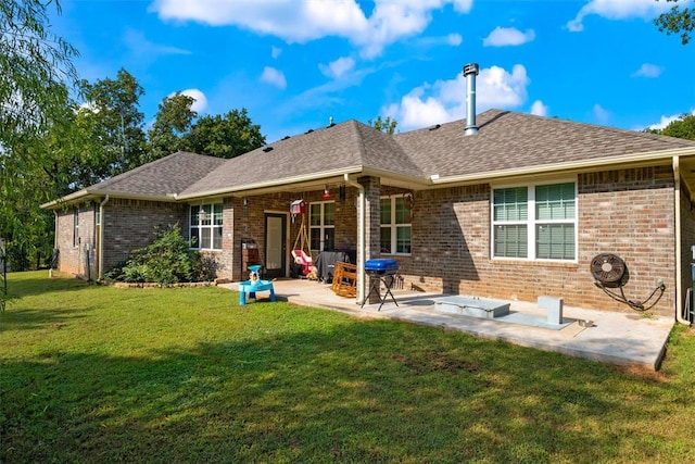 rear view of house featuring a patio area, brick siding, roof with shingles, and a lawn