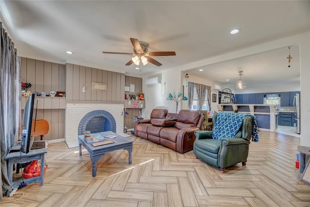 living room with a wall mounted air conditioner, ceiling fan, a brick fireplace, and light parquet floors