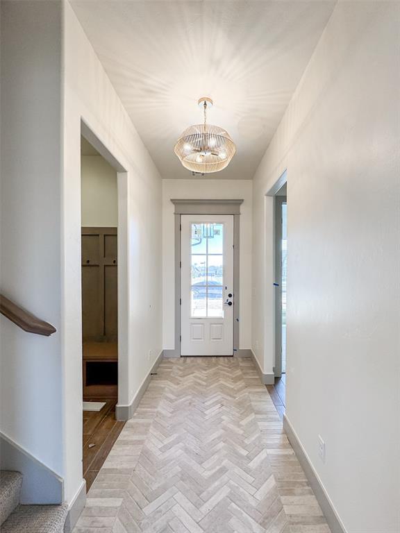 doorway to outside featuring a notable chandelier and light parquet flooring