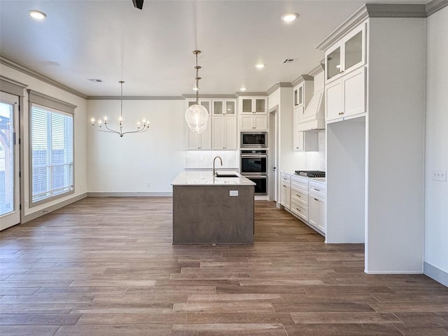 kitchen with white cabinetry, a center island with sink, stainless steel appliances, and decorative light fixtures