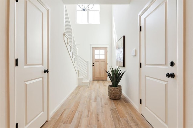 doorway to outside featuring light wood-type flooring, stairs, and baseboards