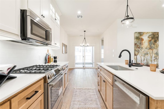 kitchen with visible vents, backsplash, appliances with stainless steel finishes, light wood-style floors, and a sink