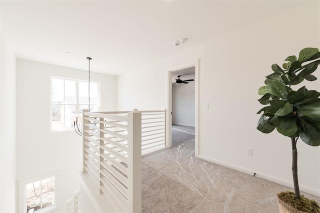 hallway featuring a notable chandelier, carpet, an upstairs landing, and baseboards