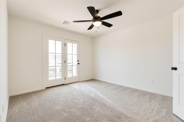 carpeted spare room with a ceiling fan, visible vents, and baseboards