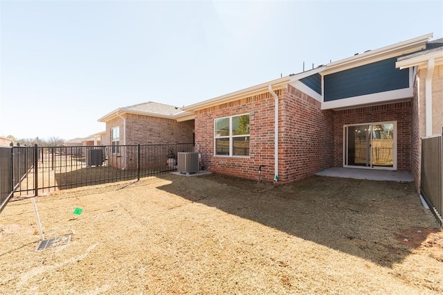 rear view of property featuring a fenced backyard, cooling unit, and brick siding