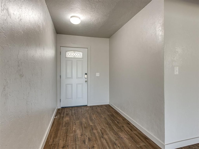 doorway to outside with a textured ceiling and dark hardwood / wood-style floors