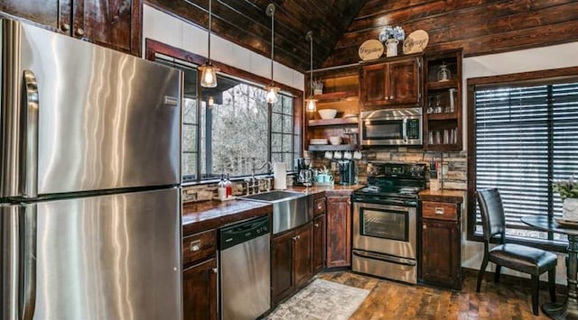 kitchen featuring vaulted ceiling, dark hardwood / wood-style floors, appliances with stainless steel finishes, decorative light fixtures, and dark brown cabinetry